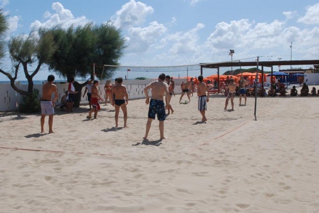 Partita di beach volley sulla sabbia con spettatori.