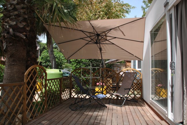 Una terrazza con sedie a sdraio sotto un grande ombrellone.