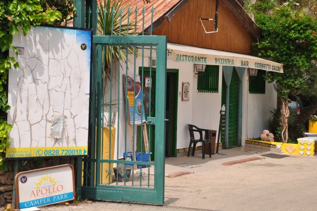 Entrata di un camper park con cancello verde e insegne.