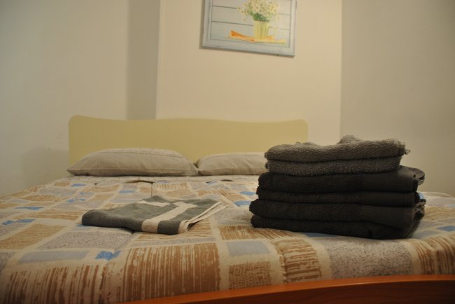 Letto con asciugamani piegati e due cuscini.
