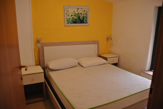 Camera con letto, cuscini e parete gialla.