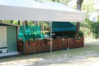 Area camping con gazebo, recinto di legno e decorazioni floreali.