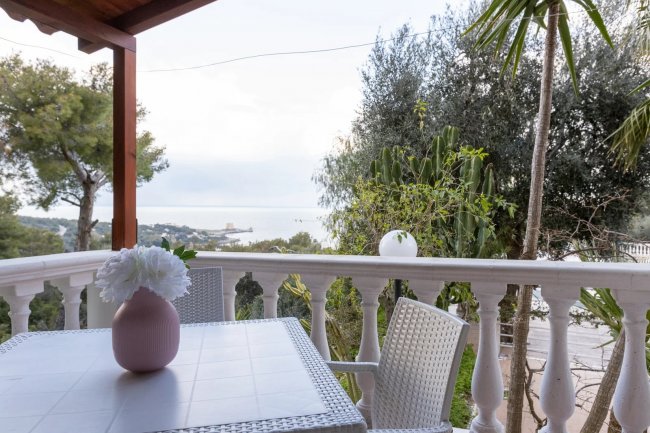 Tavolo con vaso di fiori su balcone con vista mare.
