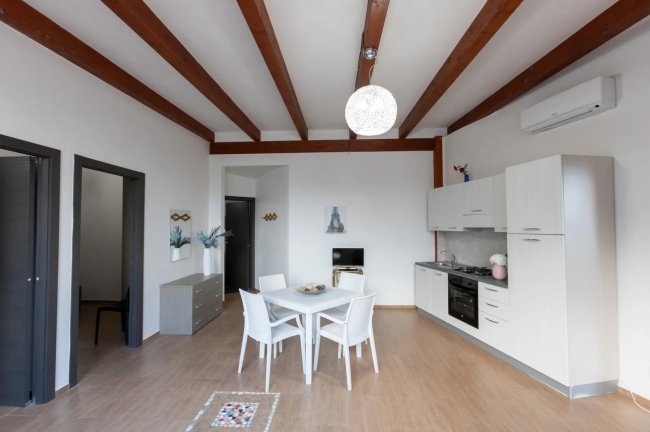 Sala da pranzo con tavolo bianco e cucina moderna.