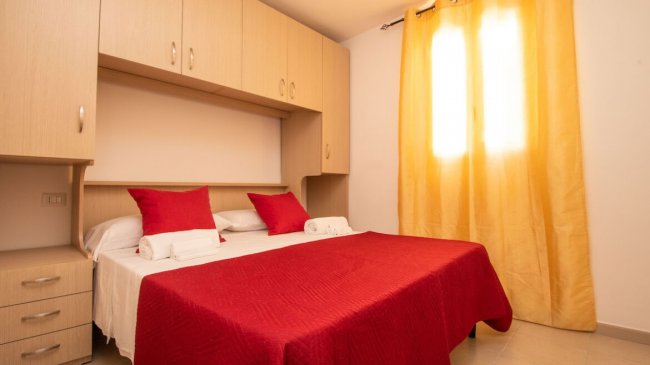 Camera da letto con copriletto rosso.