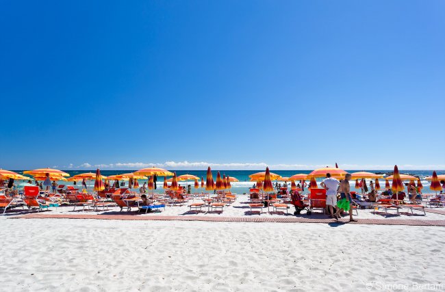 Spiaggia con sdraio, mare e cielo blu.