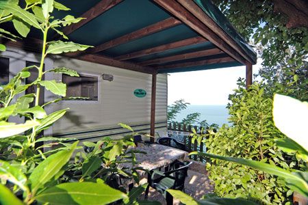 Terrazza con tavolo circondata da piante e vista sul mare.