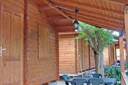 Chalet in legno con veranda, tavolo e sedie da esterno sotto un tetto inclinato.