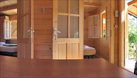 Interno di una cabina in legno con porte e finestre aperte.
