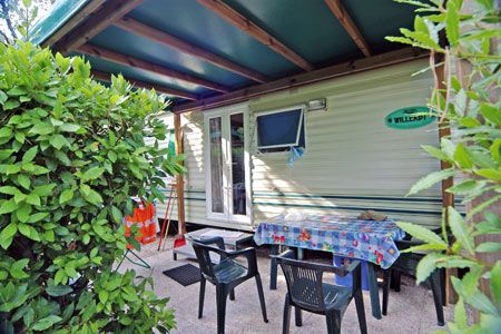 Veranda di una casa mobile con tavolo apparecchiato e sedie.