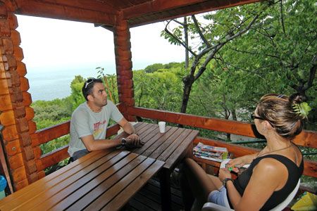 Due persone sedute su una terrazza di legno con vista mare.
