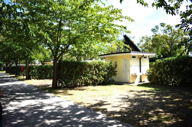 Edificio giallo tra alberi e siepi, cielo sereno.