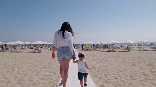 Donna e bambino camminano sulla spiaggia.