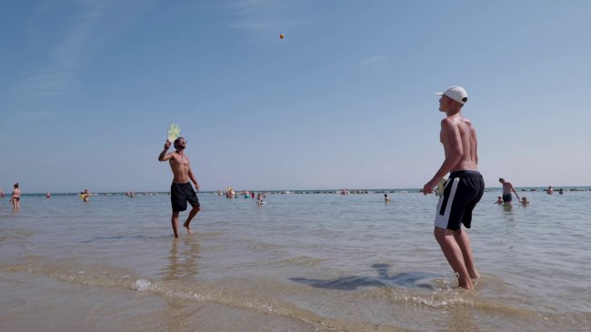 Due persone giocano a palla in acqua sulla spiaggia.