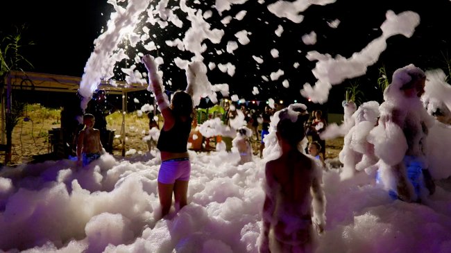 Bambini che giocano tra la schiuma di notte.