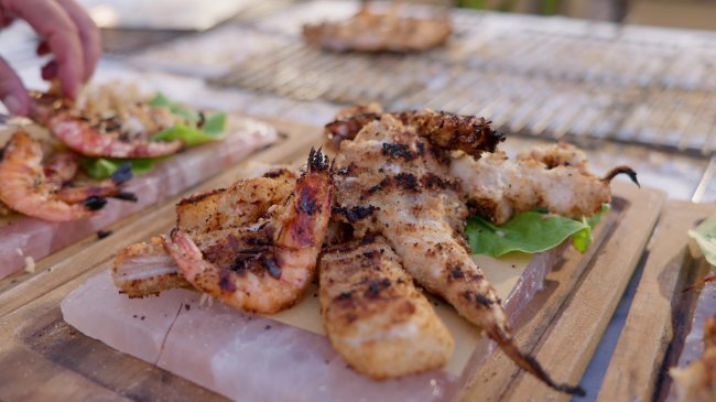 Piatti di pesce grigliato su tavole di legno.