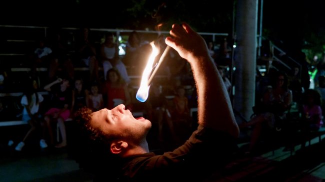 Persona esegue spettacolo di fuoco davanti a spettatori.