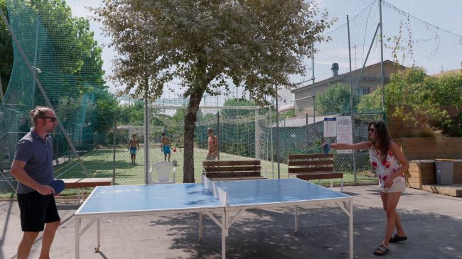 Due persone giocano a ping pong all'aperto.