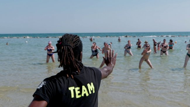 Istruttore conduce una lezione di acquagym al mare.
