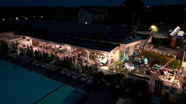 Ristorante affollato con piscina illuminata di notte.
