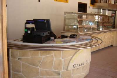 Un bancone in pietra con registratore di cassa e vetrina vuota.