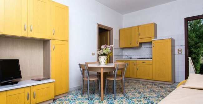 Cucina gialla con tavolo rotondo e fiori.