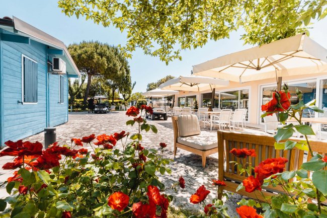 Patio con sedie, tavoli e ombrelloni bianchi.