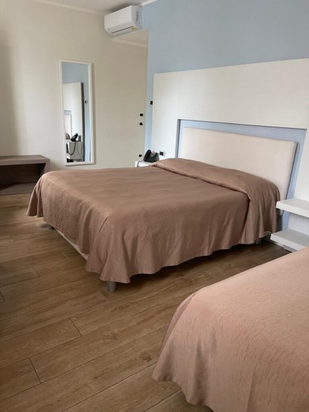 Camera d'albergo con letto matrimoniale e arredo minimalista.