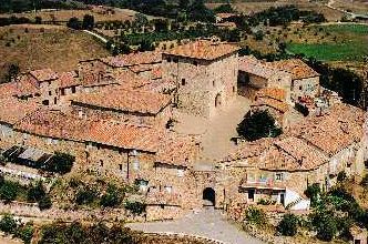 Veduta aerea di un borgo medievale con edifici in pietra e tetti rossicci.