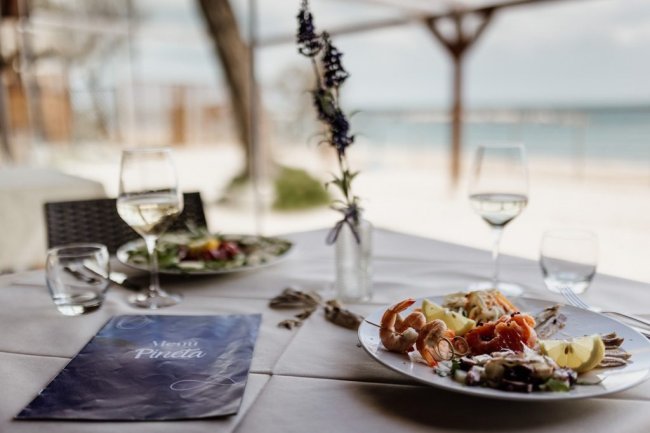 Tavola apparecchiata con piatti di pesce e mare sullo sfondo.