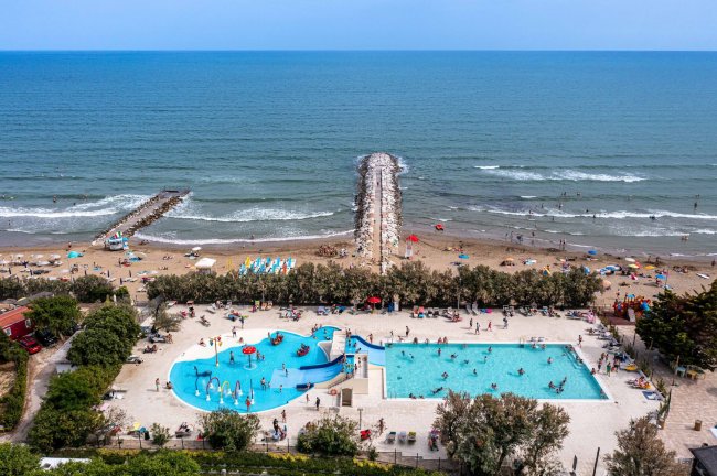 Piscine vicino alla spiaggia con ombrelloni e persone.