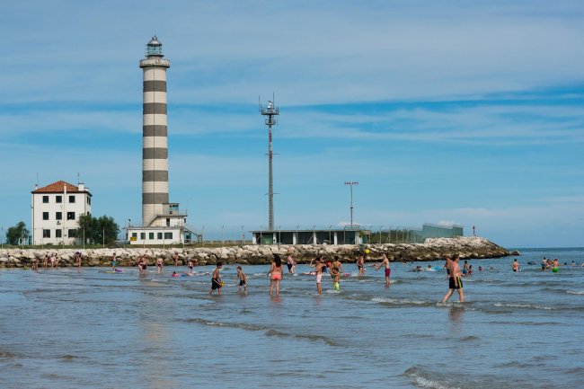 Persone in acqua vicino a un faro a strisce.