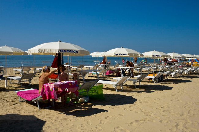 Spiaggia con lettini e ombrelloni bianchi.