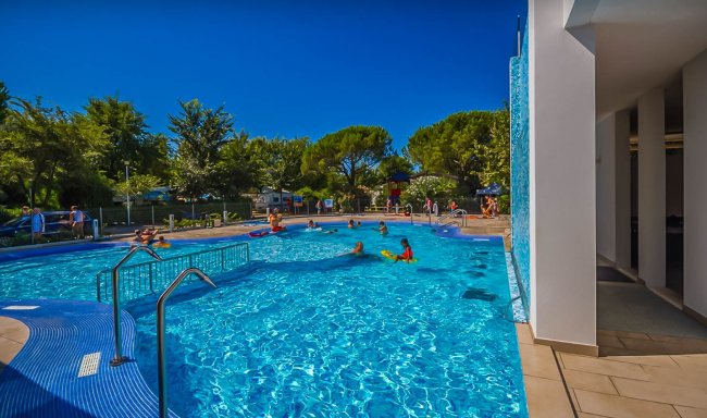 Piscina con bagnanti e ambiente verde.