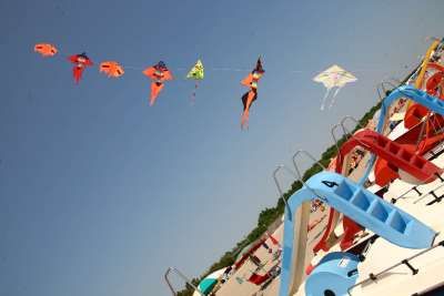 Aquiloni colorati volano in cielo sopra pedalò sulla spiaggia.