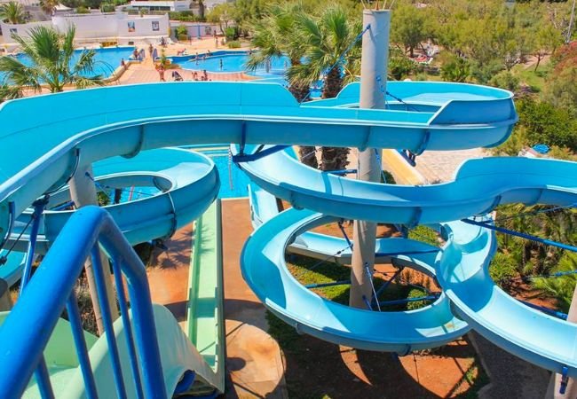 Scivolo d'acqua blu con curve, circondato da palme.