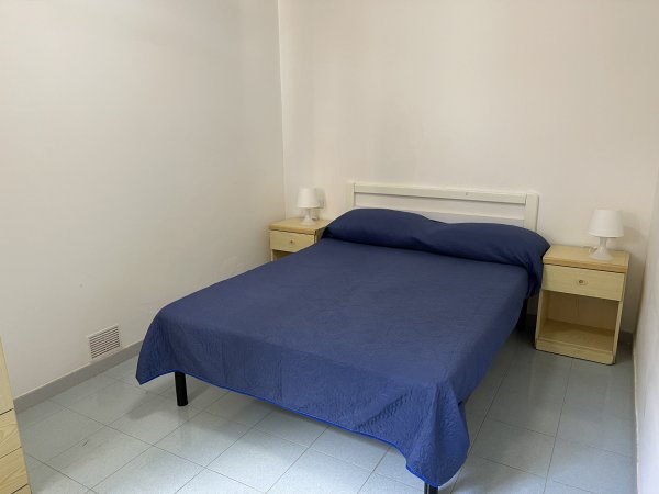 Camera con letto matrimoniale blu e due comodini con lampade.