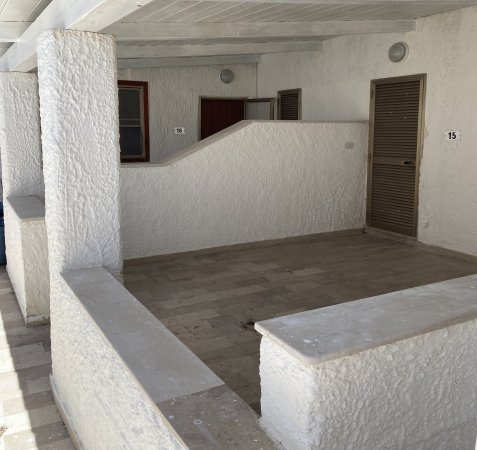 Un'ampia terrazza coperta con tre porte e pareti bianche.