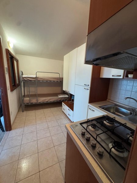 Cucina con fornelli, lavandino e letti a castello.