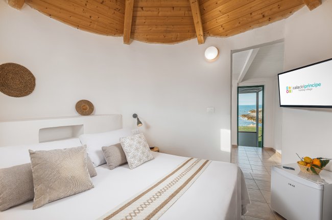 Camera luminosa con letto matrimoniale, soffitto in legno e vista mare.