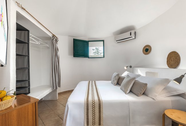 Stanza accogliente con letto matrimoniale e finestra verde aperta.
