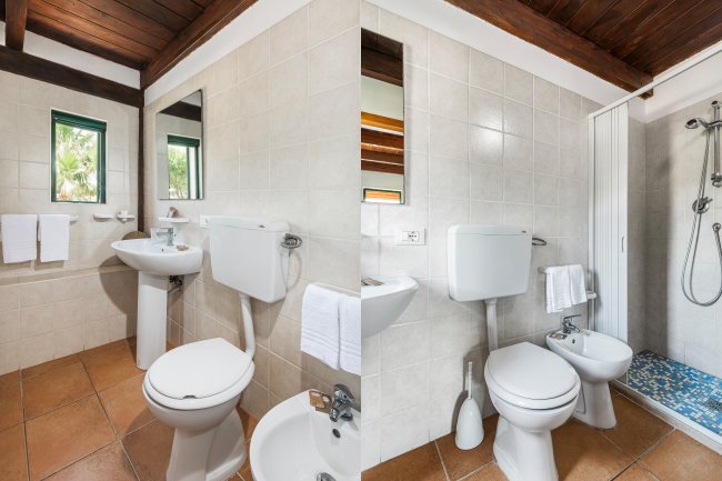 Un bagno con doccia, WC e lavandino. Pareti piastrellate e soffitto in legno. Asciugamani appesi.