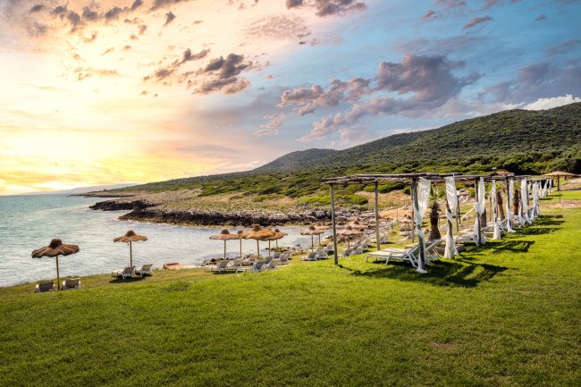 Spiaggia con lettini e ombrelloni al tramonto.