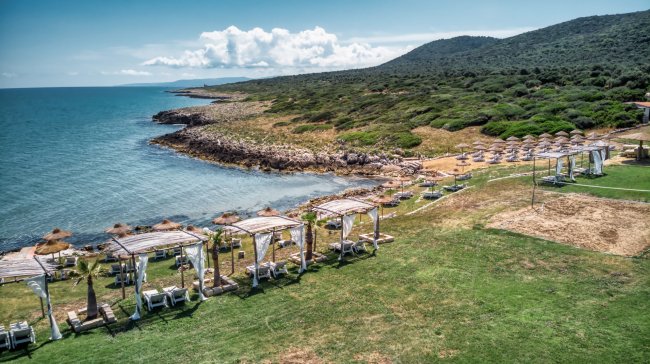 Spiaggia con gazebo e lettini lungo una costa verde.