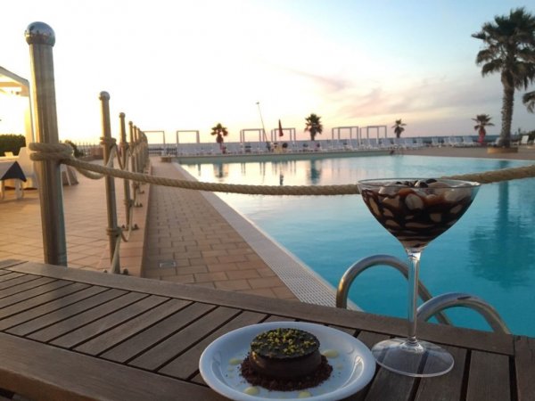 Dolce e cocktail a bordo piscina al tramonto.