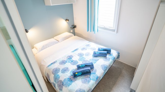 Una camera da letto con un letto matrimoniale, coperte colorate e asciugamani.